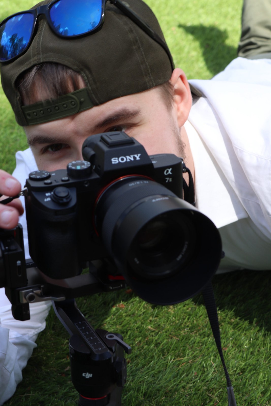Omni Solutionsin kuvaaja kuvaa Sony-kameralla gimbaalilla nurmikolla pystyvideota varten